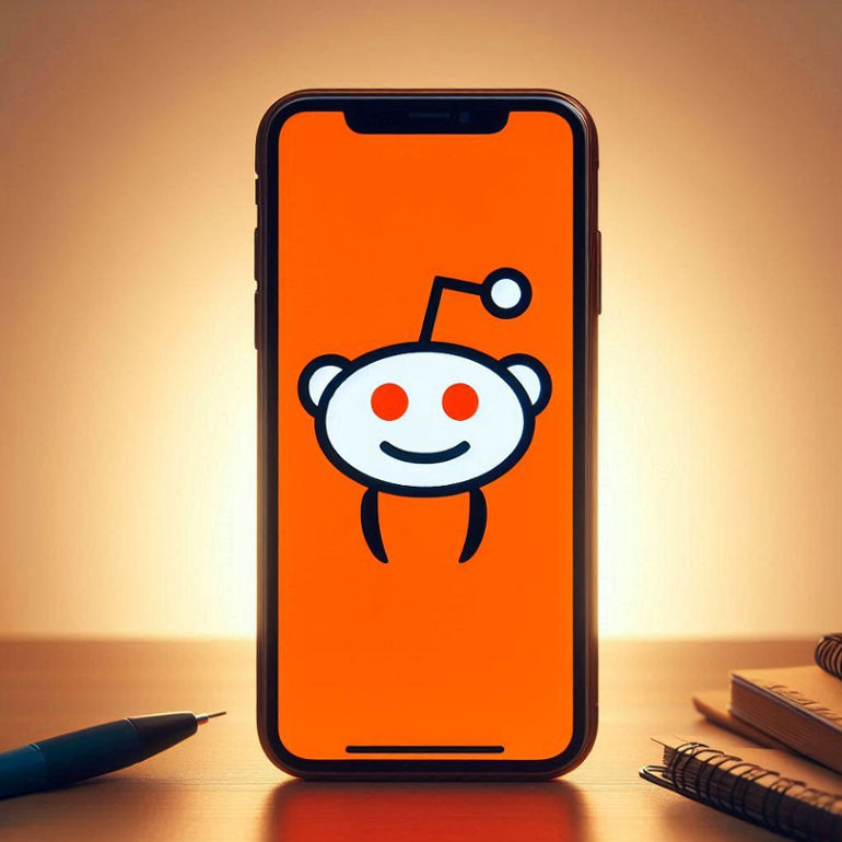An iPhone screen displaying a bright, orange Reddit logo with a friendly expression and a single antenna.